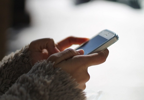 Die Hände einer Person, die auf dem Smartphone tippt.