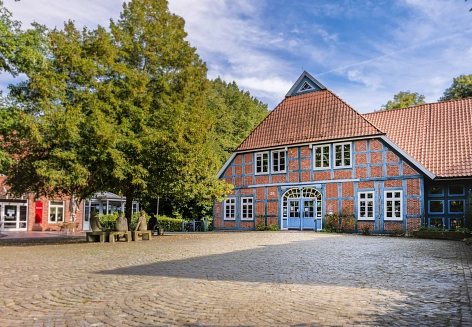 Der Vorplatz mit grünem Baum und altem Gebäude von Murkens Hof